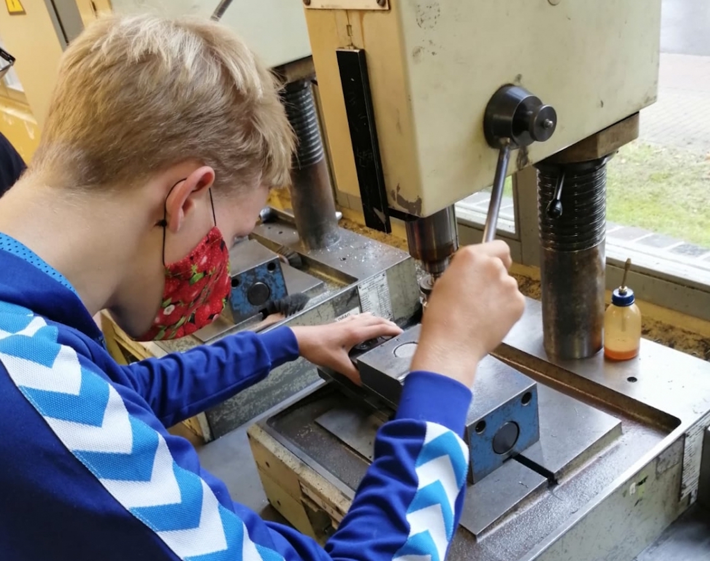 Junge mit Maske an Maschine