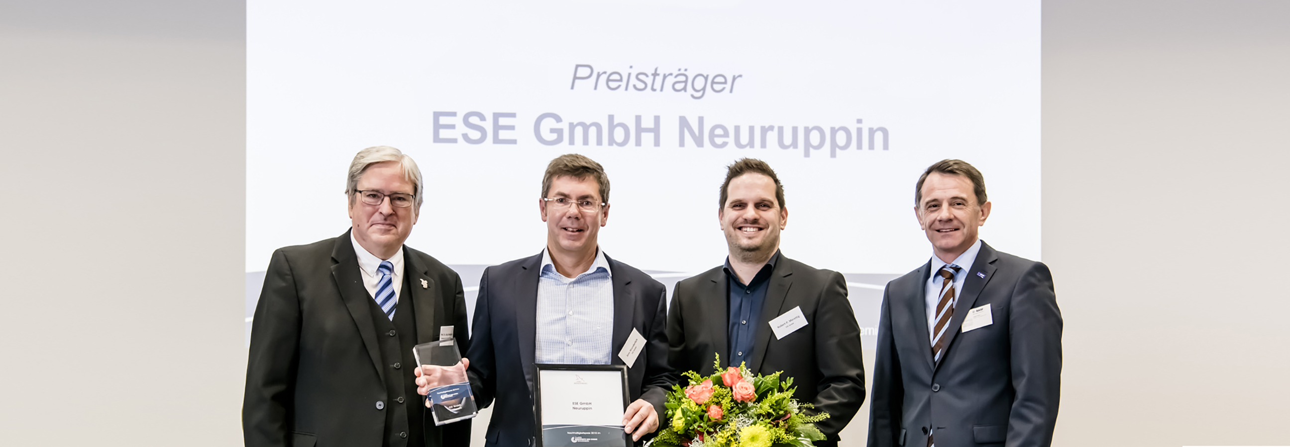 4 Herren mit Blumen und Urkunden auf dem Podium