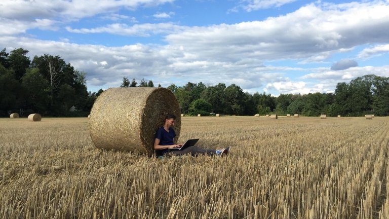 Person sitzt mit seinem Laptop an einem Strohballen