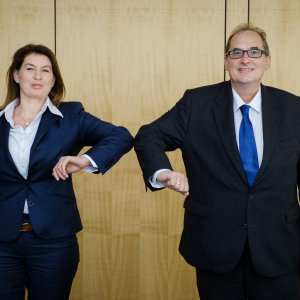 Frau und Mann grüßen sich mit Ellenbogen